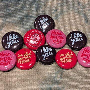 a variety of buttons with sayings on them. Sayings include 'I like you' and 'I'm glad you're here'