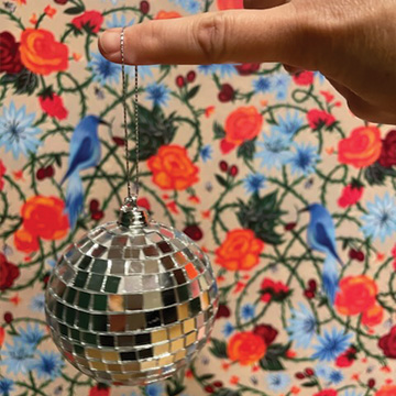 a small disco ball in front of a floral wallpaper background