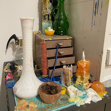 a wood shelf displaying various candles with an open draw holding boxes of tarot cards