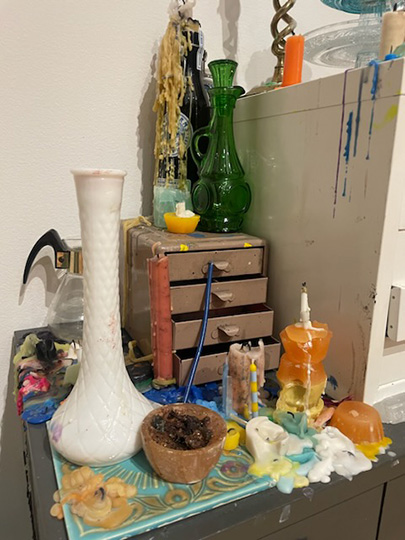 a wood shelf displaying various candles with an open draw holding boxes of tarot cards