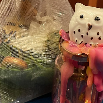 an owl figurine sitting on melted glass on top of a bottle and a satchel for potpourri