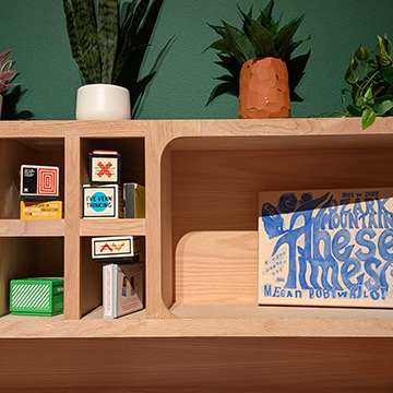a wooden bookshelf filled with knickknacks against a dark green wall