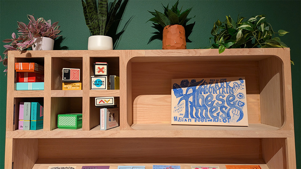 a wooden bookshelf filled with knickknacks against a dark green wall