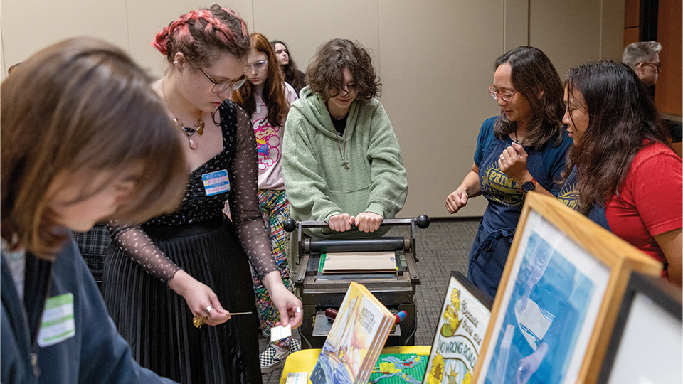 A group of young artists working on creating a print with a press