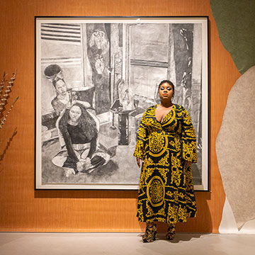 Artist glyneisha standing in front of her drawing titled "For Us by Us"