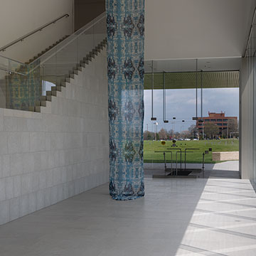 A long, 2 story textile art piece hangs in the Nerman Museum next to the stairs