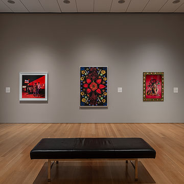 View of the PhotograpHER exhibition at the Nerman Museum showing three works along a wall with a bench in the foreground