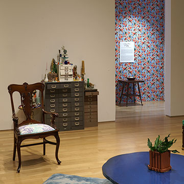 a chair, filing cabinet, and wallpapered wall, part of the salon installation at the Nerman Museum