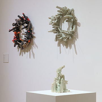 three sculptures hanging on a wall and one on a pedestal, on display at the Nerman Museum