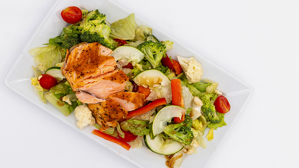 a salad with chicken on a white rectangular plate